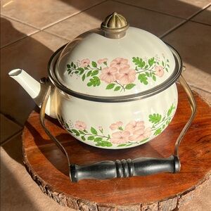 Vintage enamelware teapot with pink floral decorations and brass handle accents